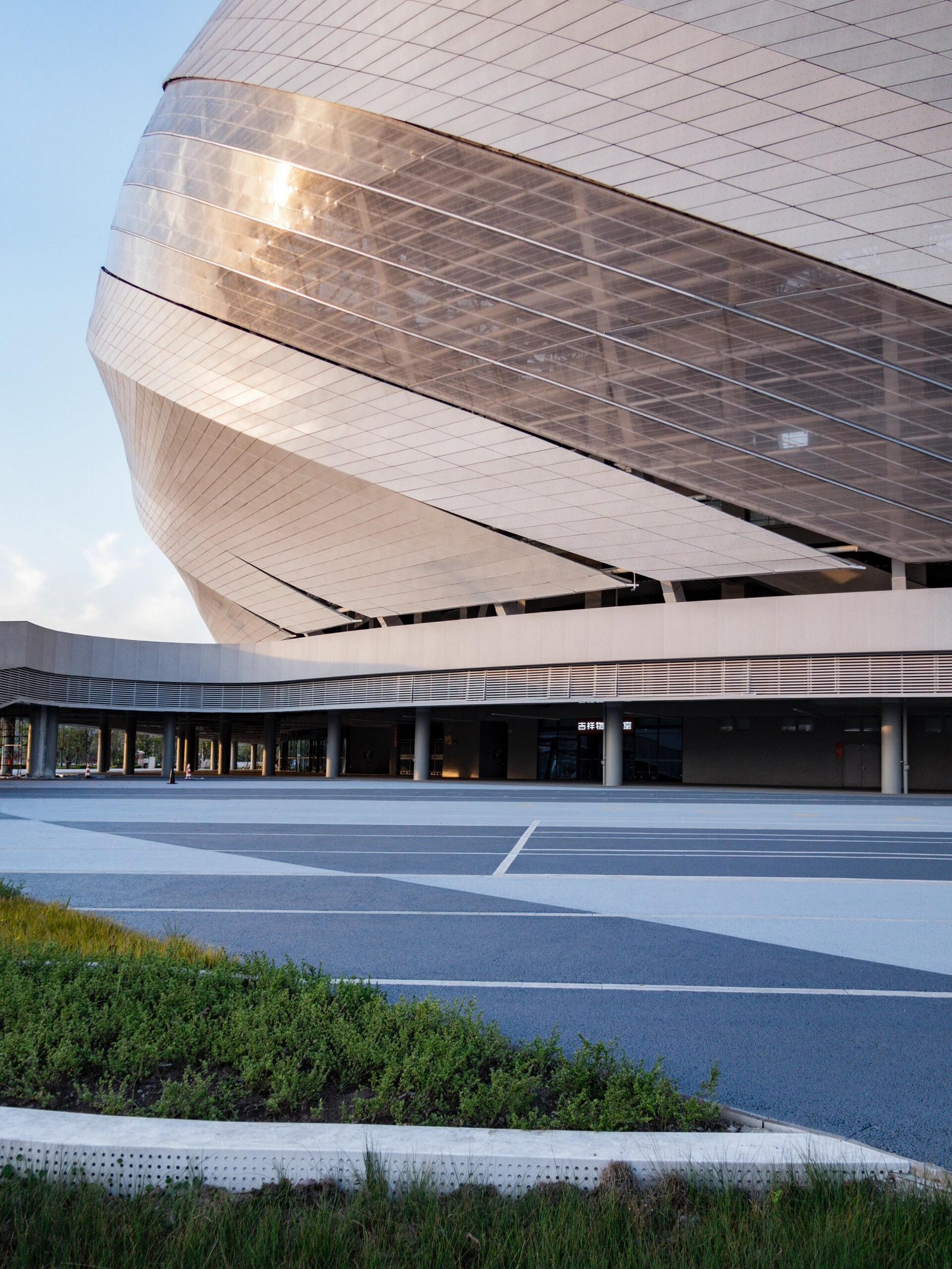 Close-up of the stadium facade, highlighting the seamless integration between the white ETFE tensile fabric veil and the massive 100,000 sqm LED transparent grille screen.