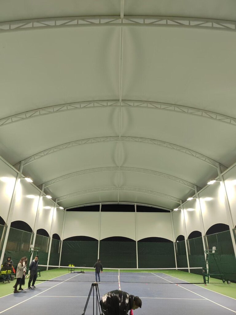 Natural lighting and clear span interior of a SkyTensile indoor tennis court.